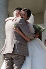 Happy couple embraces on their wedding day, a tender moment captured outdoors.