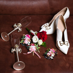 Elegant wedding details: shoes, champagne flutes, and floral boutonnieres.