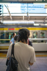 People standing in line at a Japanese train station platform, waiting for a subway train to arrive. Urban transportation, daily commuting, and modern lifestyle concept in Tokyo, Japan
