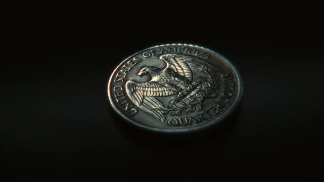 3D animation of a United States quarter dollar coin spinning on a dark surface and landing on tails, symbolizing chance, gambling and decision making.