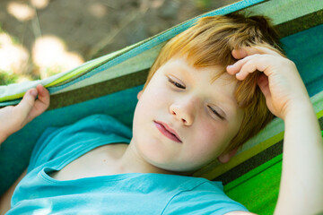 close up of face dreaming boy lying in the hammock outside in nature