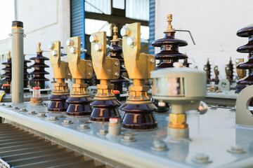 Close-up view of the upper part of a power distribution transformer with connectors and ceramic...