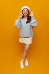Asian woman posing with OK hand gesture in casual fashion outfit expressing confidence playful energy positivity modern lifestyle isolated on yellow background