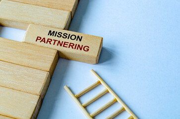 Mission Partnering text written on a wooden block placed on a ladder illustrating purpose driven objectives and direction.