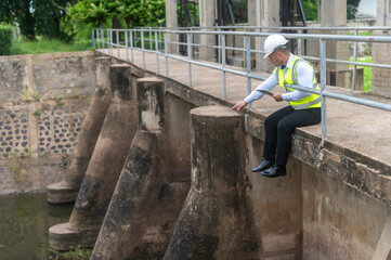A male dam engineer is sitting and checking the water level in the dam and recording the water level