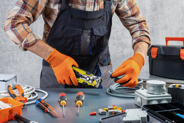 Electrician strips insulation from electric wire with hand tool. Professional electrician job.