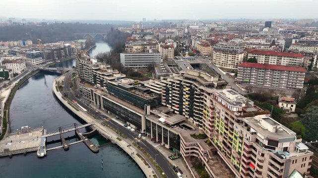 Drone aerial view of Geneva with Rhone river Batiment des Forces Motrices riverside buildings and skyline on a cloudy winter day