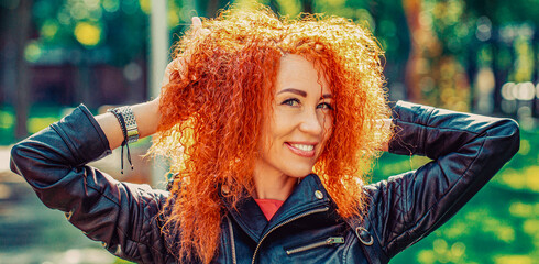 Smiling happy woman curly red hair. Closeup portrait woman, girl red hair, toothy smile walking in park forest outdoors