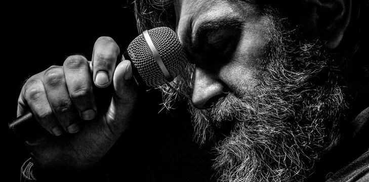 Man attends karaoke. Bearded man singing with microphone. Black and white