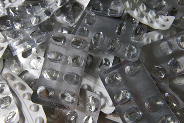 Empty blisters of pills, capsules, and medications. Symbol of finished treatment or drug overuse. Used pharmaceutical packaging. Close-up of medicine foil packaging.