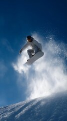 Snowboarder jumping through air with blue sky.