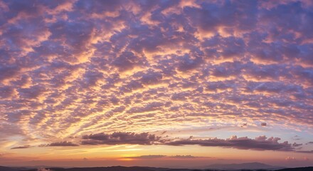 Obraz premium Stunning skyscape at dusk featuring dramatic purple and orange altocumulus clouds creating a breathtaking mackerel sky effect