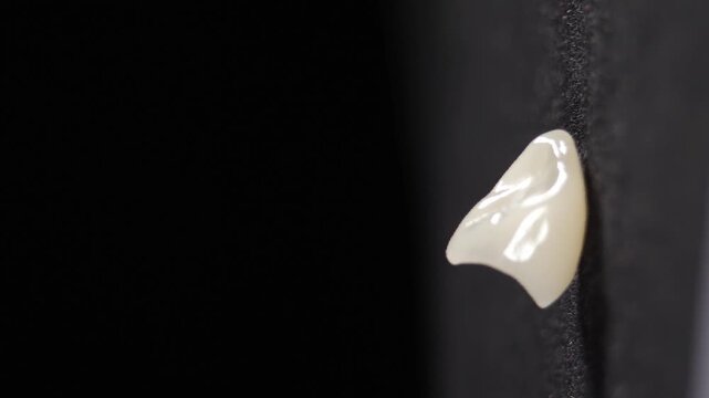 Artificial dental crown model shot on black background. Dental teeth veneers. Vertical footage. Removable partial denture, mandibular prosthesis. 4 k video