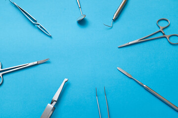 assorted surgical and dental instruments arranged in a flat lay on a vibrant blue background,...