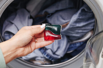 Hand holding laundry detergent pod. Washing capsule for clothes cleaning. Household product for washing machine use. Liquid gel detergent in plastic capsule. Modern cleaning concept closeup.