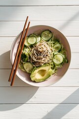 Cold ramen salad bowl with cucumbers, lettuce, avocado slices, and sesame dressing in pastel bowl