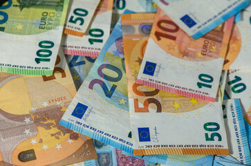 Euro bills closeup spread across wooden table surface