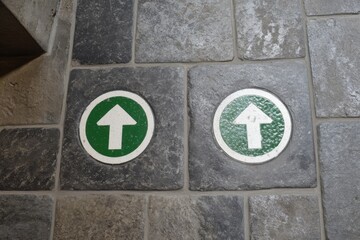 Two green upward-pointing arrows on light gray stone tiles