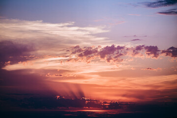 A breathtaking sunset sky filled with vibrant orange, purple, and pink hues. The clouds are textured and dynamic, creating a sense of movement and energy. 