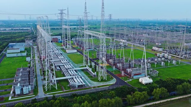 Aerial shot of a high voltage power station with transmission towers and electrical grid infrastructure in a rural landscape