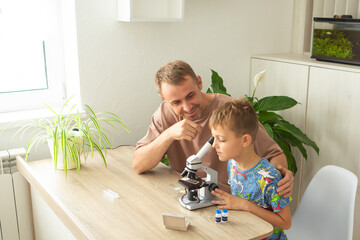 Father and son explore biology together at home using a microscope to study plants in a modern, cozy environment