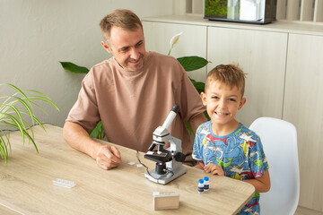 Father and son explore biology at home using a microscope to examine plant samples together