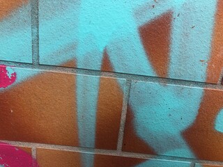 Close-up of urban graffiti on textured brick Berlin wall orange blue teal purple