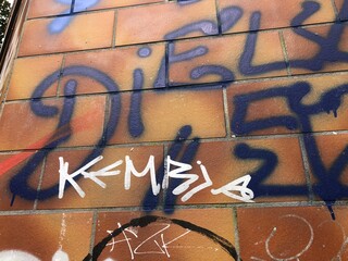 Close-up of urban graffiti on textured brick Berlin wall orange blue white