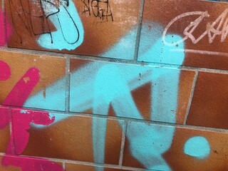 Close-up of urban graffiti on textured brick Berlin wall orange blue teal purple