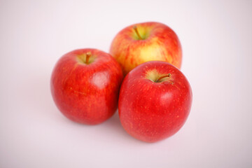 Three ripe red apples on a white surface