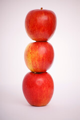 Three red apples stacked on top of each other against a white background.