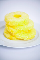 Stack of pineapple slices on a white plate