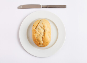 Bread roll on a plate with a knife