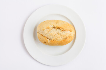 Freshly baked bread roll on a white plate against a clean white background.