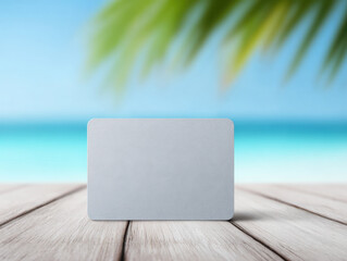 Blank credit card on wooden deck with tropical beach and palm leaves background