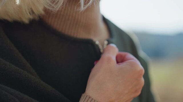 Close up of wool coat fabric with zipper detail and part of hand zipping up jacket, focus on texture of clothing in natural daylight, symbolizing warmth, autumn style seasonal outdoor comfort