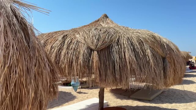beach with thatched roofs that create a cozy atmosphere.The sand on the beach is light, giving a sense of cleanliness and freshness.he beach is a perfect place to unwind and escape the hustle and bust
