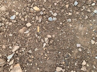 A high-angle, detailed shot of rough, broken earth mixed with small and medium-sized rocks and pebbles, creating a rich natural texture.