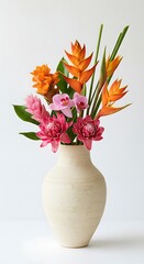 Vibrant floral arrangement featuring various tropical flowers in a cream-colored vase against a plain white backdrop.