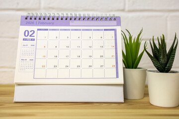 The desktop calendar for February 2026 is on the table.