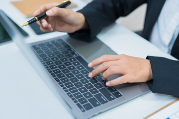 Fototapeta premium Asian businesswoman's hands typing on laptop keyboard and sitting in office