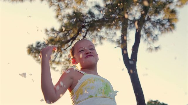 ni&ntilde;a feliz jugando divertida con la espuma de aerosol que le cae desde arriba viviendo y disfrutando de su infancia al aire libre en un parque en la naturaleza con un hermoso atardecer 