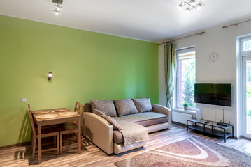 Bright Modern Living Room With Green Accents and Large Windows Opening to Nature