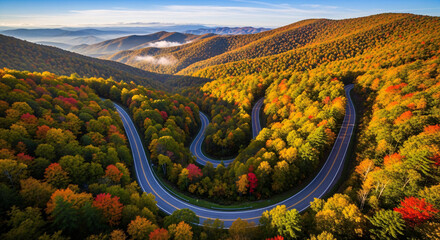 An aerial view of a winding road snaking through a vibrant autumn forest in the mountains.