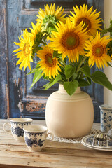 Girasoli su vaso di ceramica sopra un tavolo di legno con alcuni oggetti da cucina sparsi