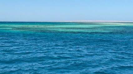 Red sea and Sinai mountains on a background. Tours to Egypt, travel and tourism concept.An aerial perspective showcasing the vibrant red sea desert coast, a colorful coral reef, and the stunning blue 