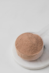 Protein chocolate powder scoop on marble surface. Copy space