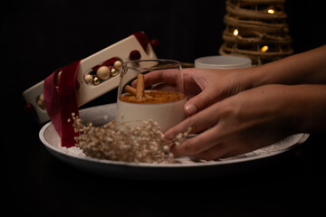 Woman holding glass of rompope with cinnamon sticks on christmas decorated tray
