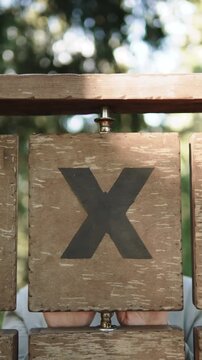 Woman with poker face turns with wooden chip with an X on it, vertical video. Symbolism of denial, prohibition, setting personal boundaries, psychological defense.