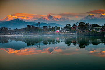 Sunrise over the Himalayas with Reflections on Phewa Lake The majestic Annapurna range glows in golden hues at sunrise, with Machapuchare’s iconic peak rising above the clouds. © Sanoyatra